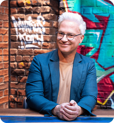 Markus sitzt vor einer Mauer und lächelt